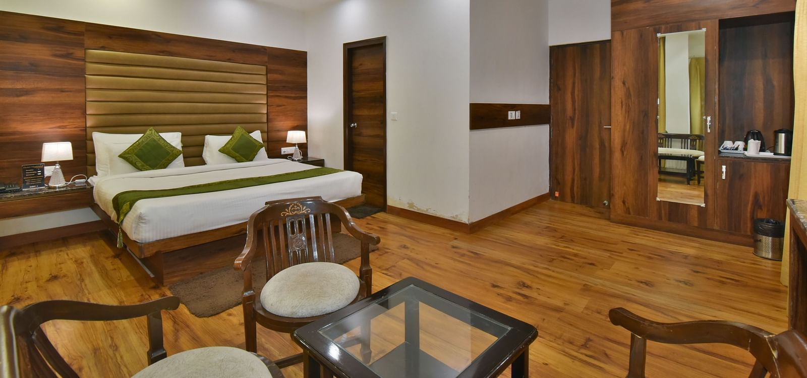 A large bed placed in front of two sofas at the Luxury Room Without Balcony at DLS Highland Resort and Spa, Mussoorie.